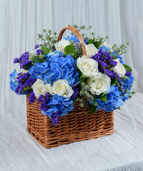 กระเช้าดอกไม้โทนสีฟ้า ขนาด 8x10x8 นิ้ว โดดเด่นด้วยดอกกุหลาบและดอกไฮเดรนเยีย พร้อมดอกแซมอีกหลายชนิด