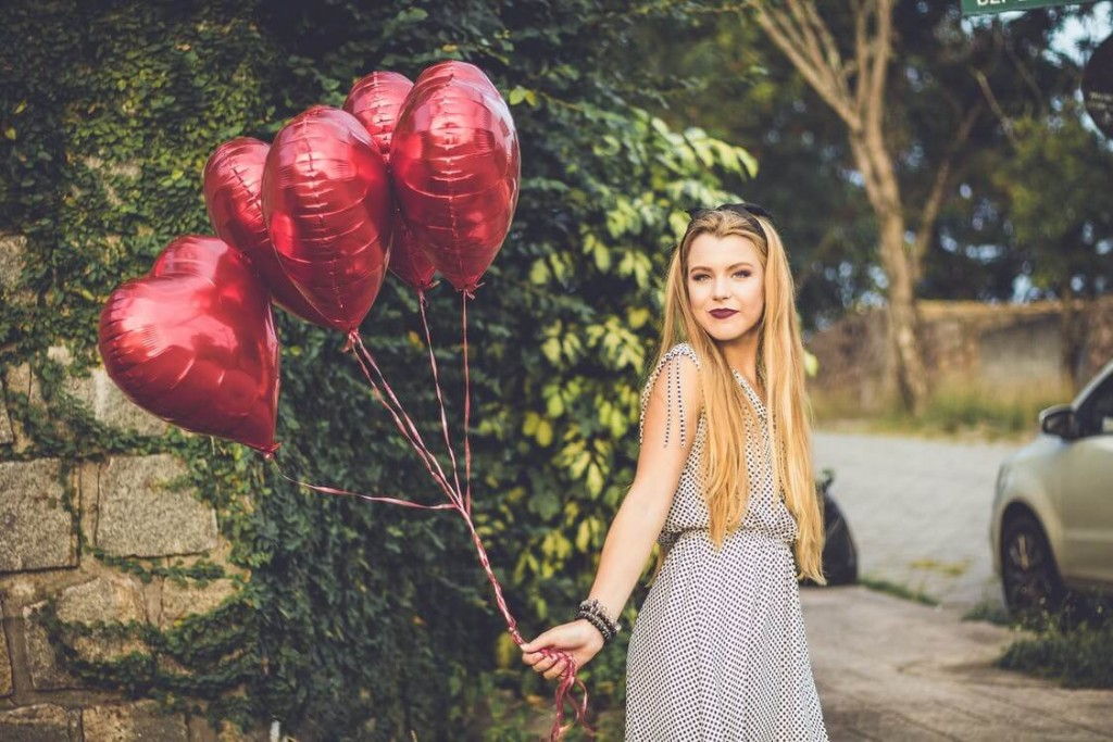 Women holding several of red balloons